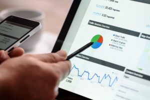 A person using a pen to point at a pie chart displayed on a tablet.