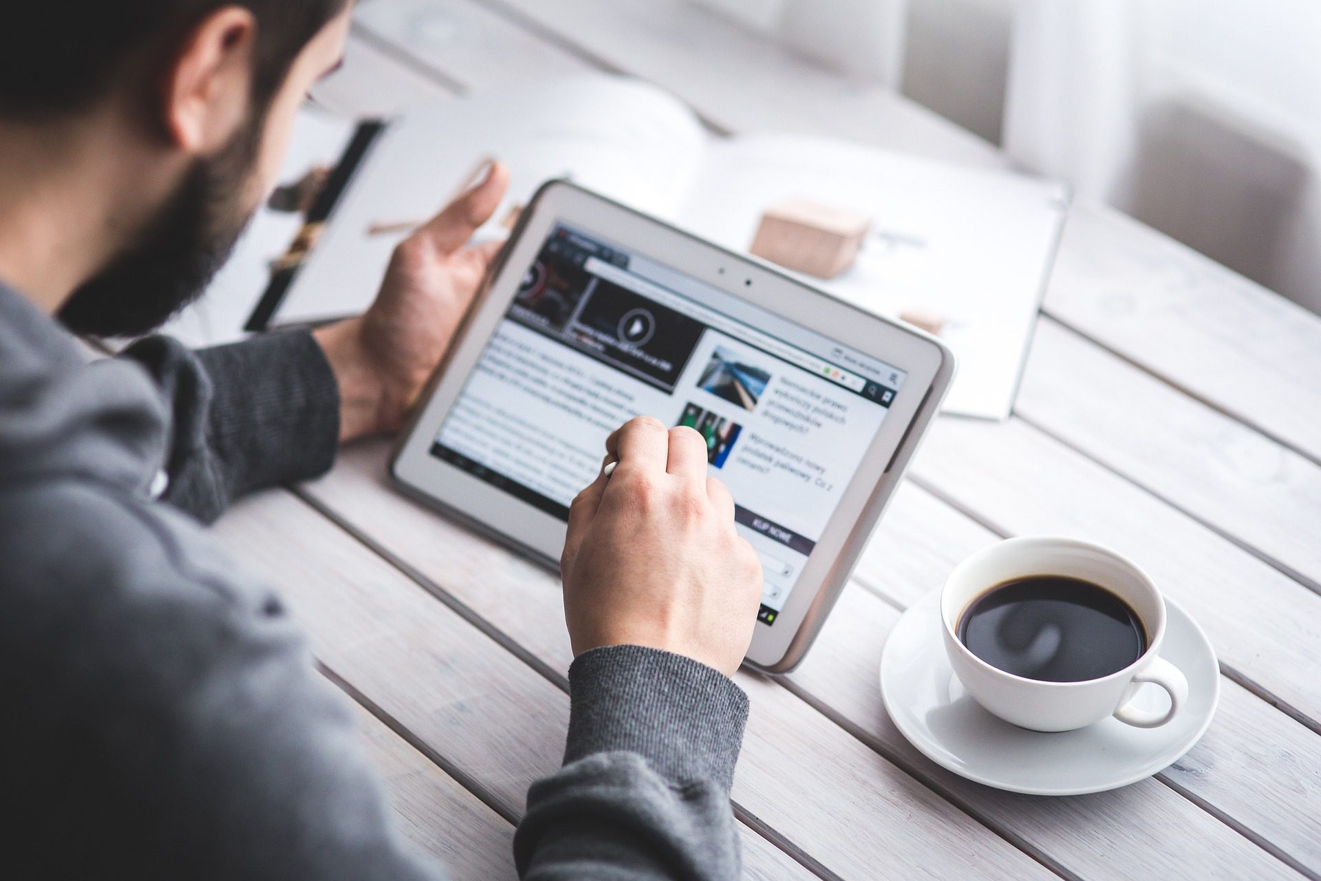 A man reading a tablet with a cup of coffee