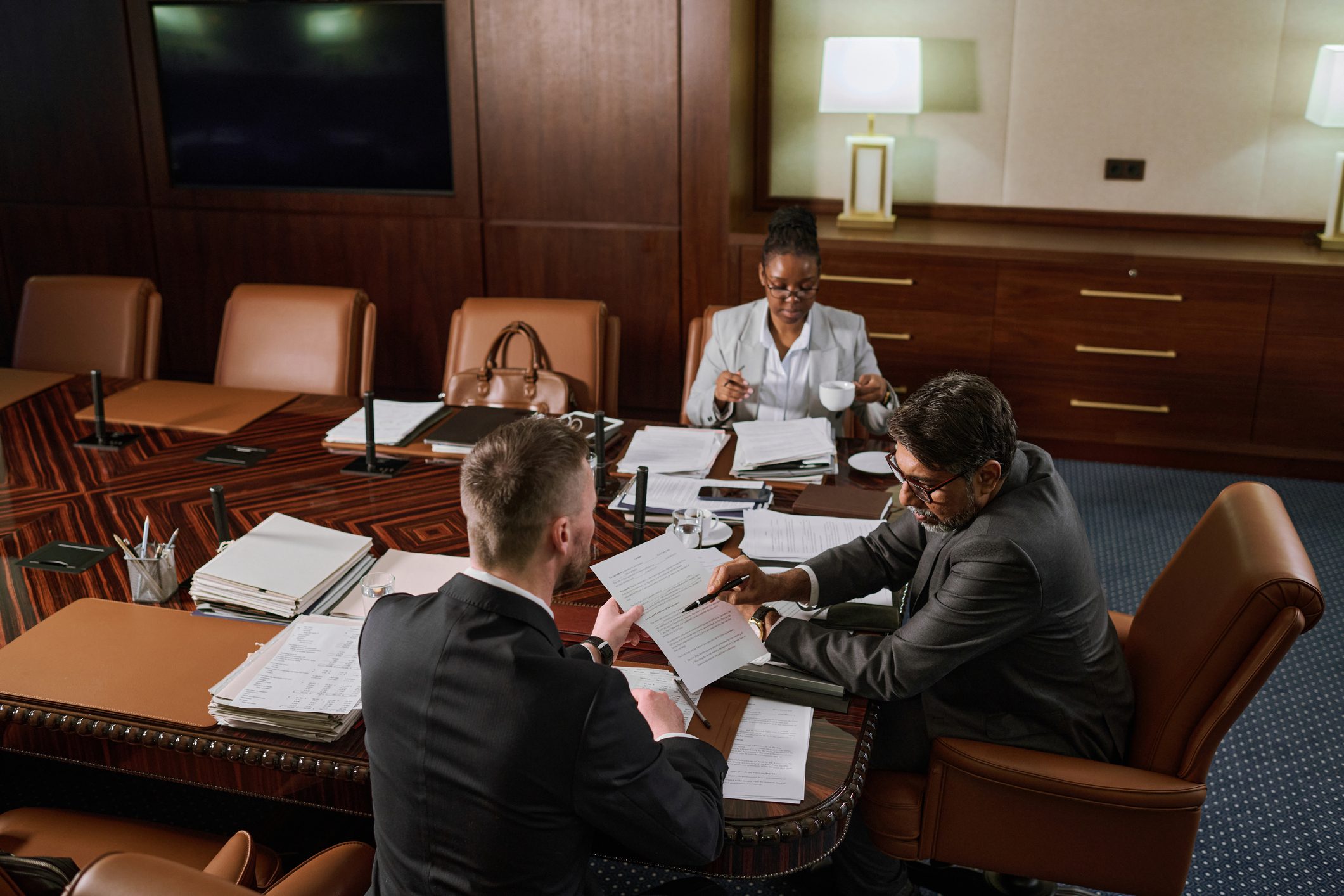 Legal professionals collaborating on legal content marketing documents in a conference room, reviewing strategy materials for law firm website content