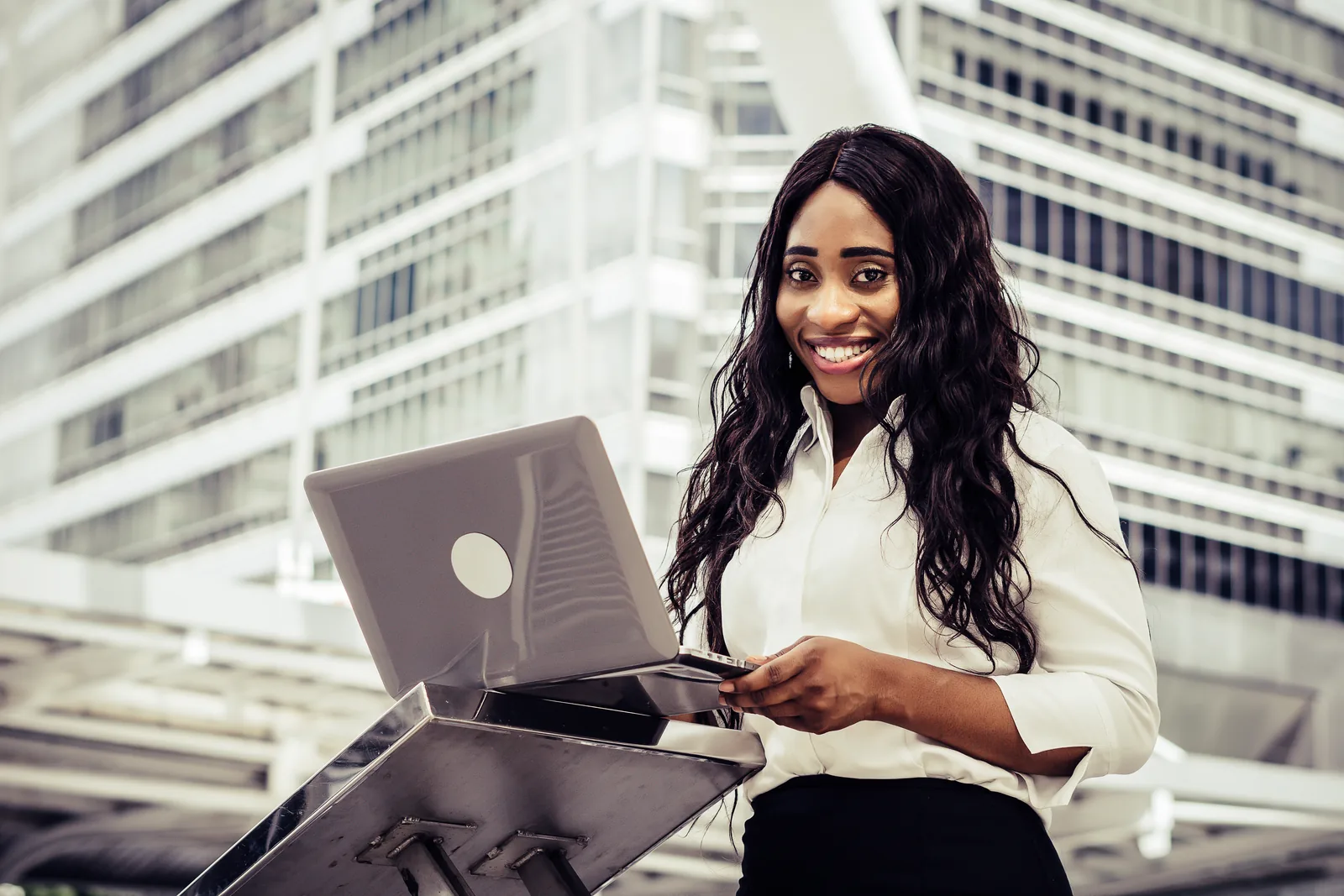 Smiling attorney using a laptop outdoors near office buildings, representing estate planning marketing