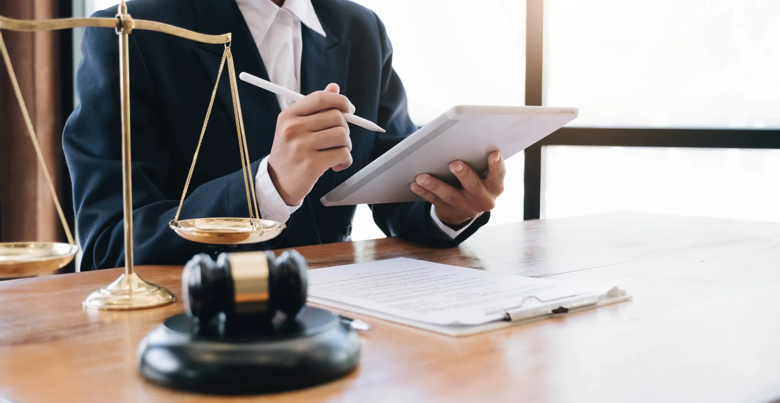Family law attorney reviewing case documents on a tablet, scales of justice and gavel on desk