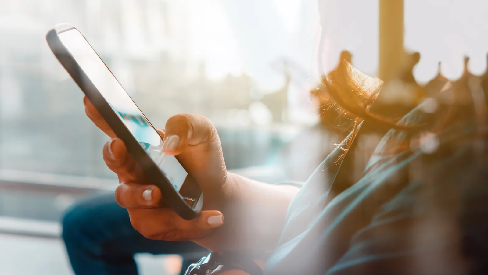 Person using a smartphone, illustrating how spoken queries to AI assistants surface different sources than typed searches.