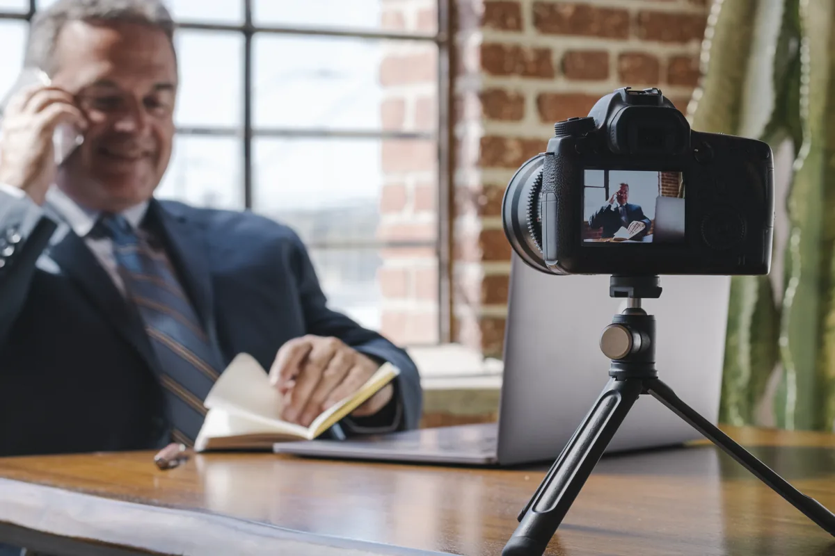 Lawyer at a desk being filmed by a camera on a tripod for a law firm video