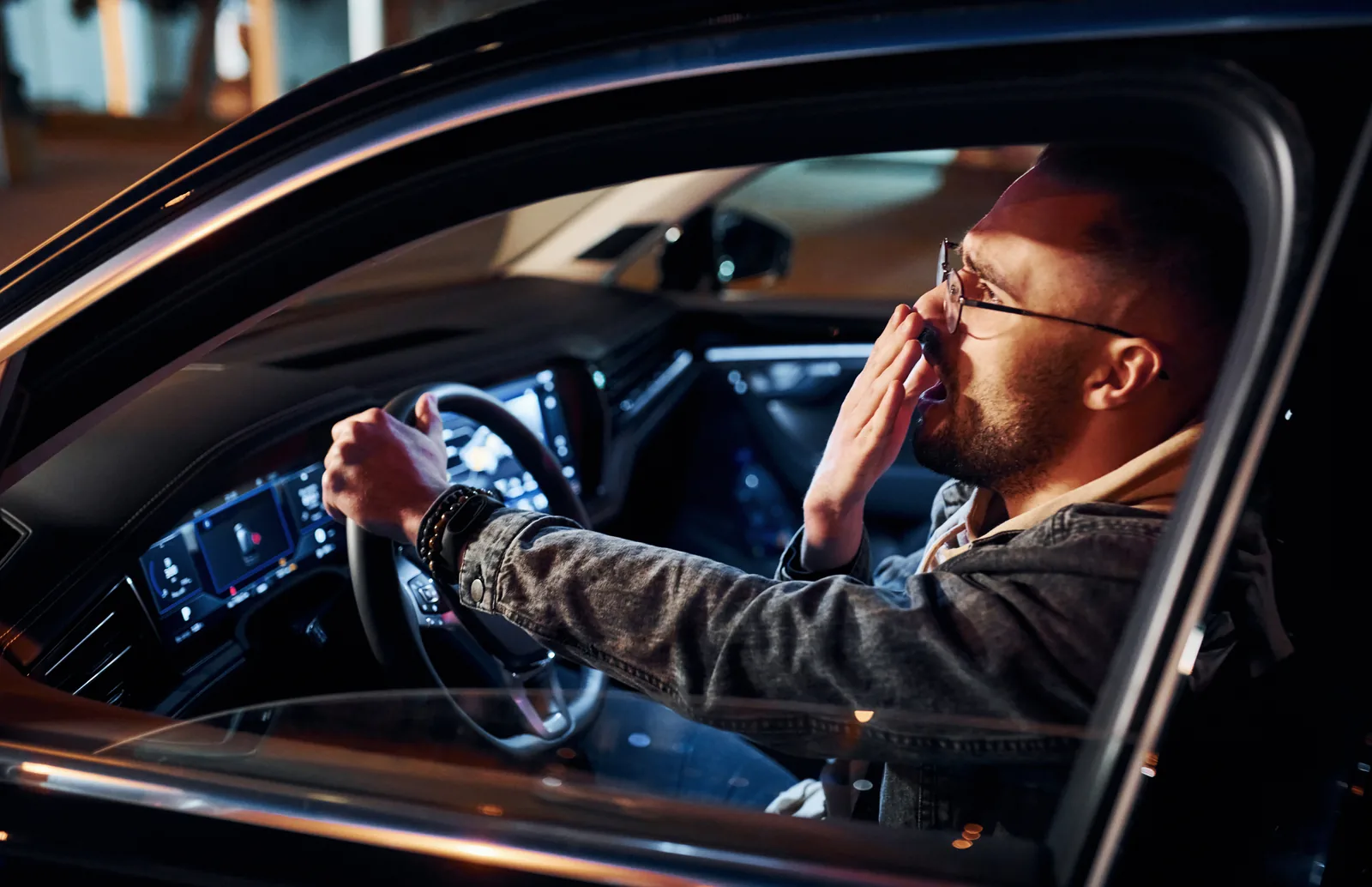 Drowsy Driving Prevention Week: tired driver yawning at the wheel at night