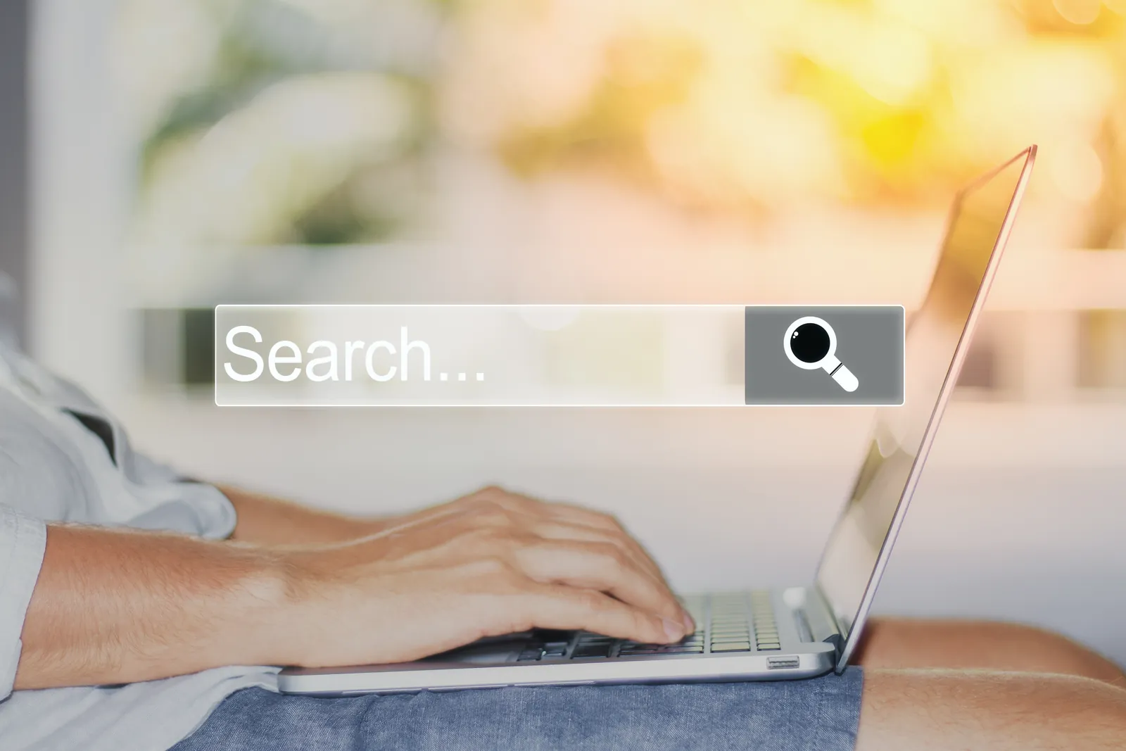 Hands typing on a laptop behind a search bar