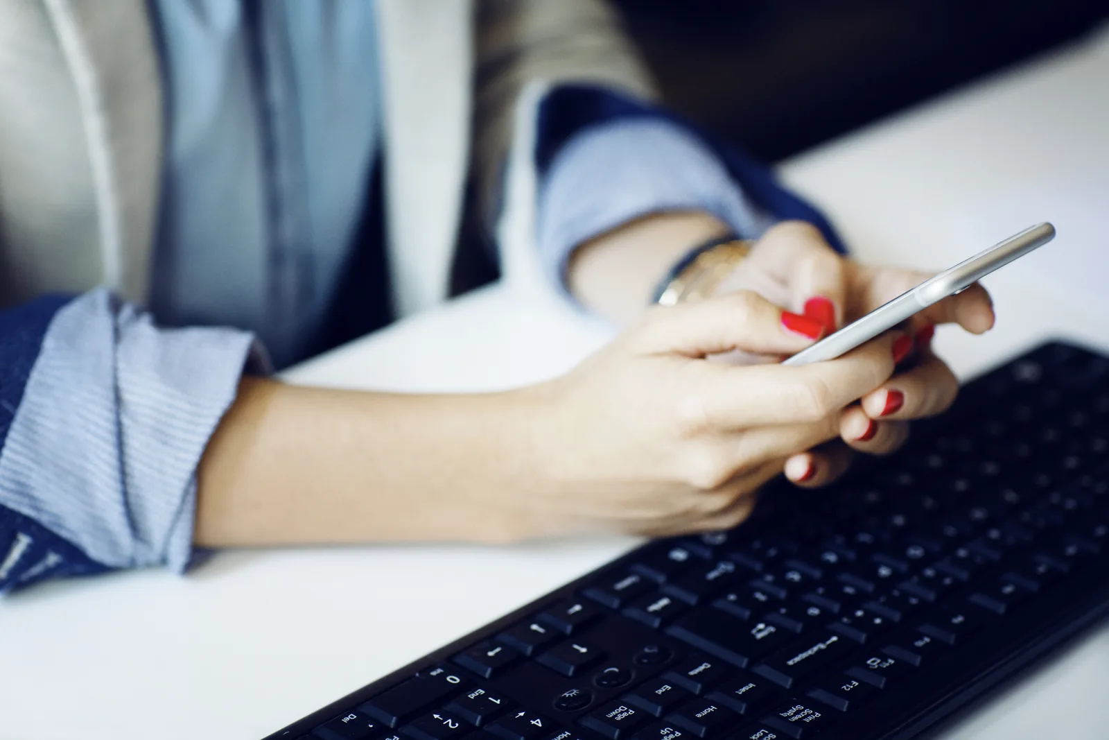 Text message marketing for law firms: hands holding a smartphone above a keyboard